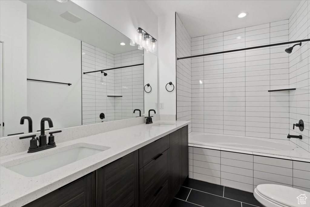 Full bath with tiled shower / bath combo, recessed lighting, double vanity, tile patterned flooring, and toilet