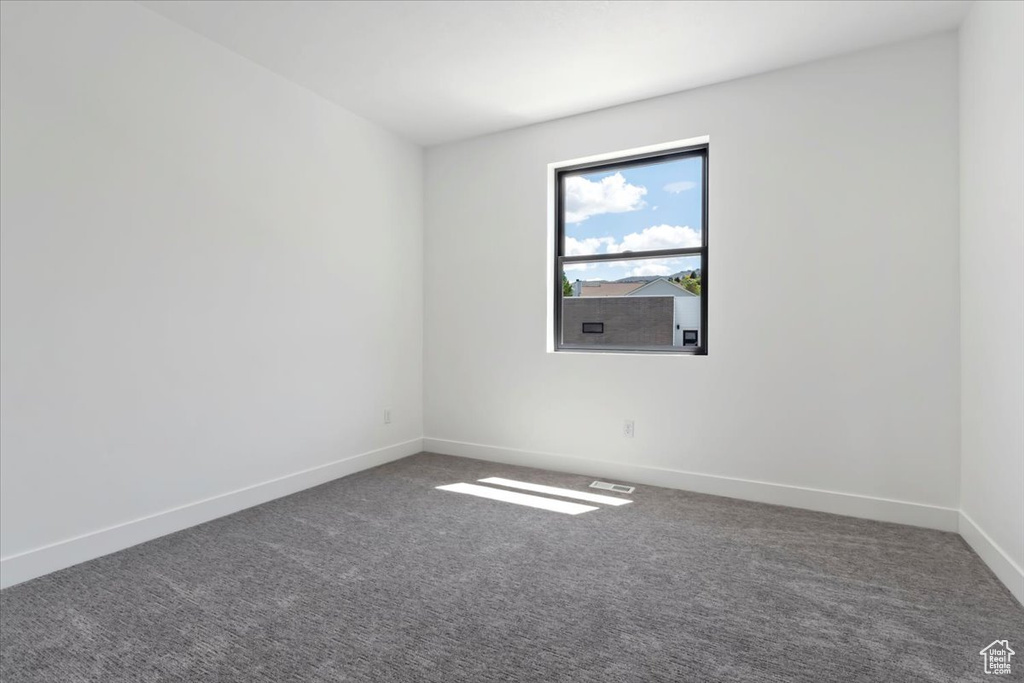 Spare room featuring carpet flooring and baseboards