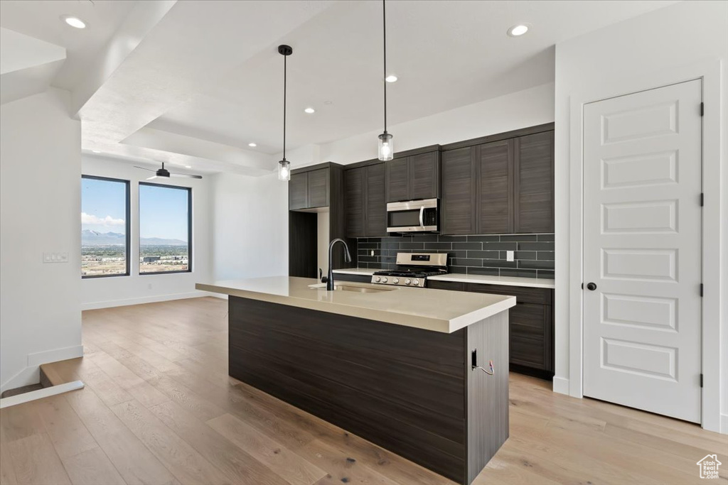 Kitchen featuring appliances with stainless steel finishes, a sink, backsplash, light countertops, and baseboards