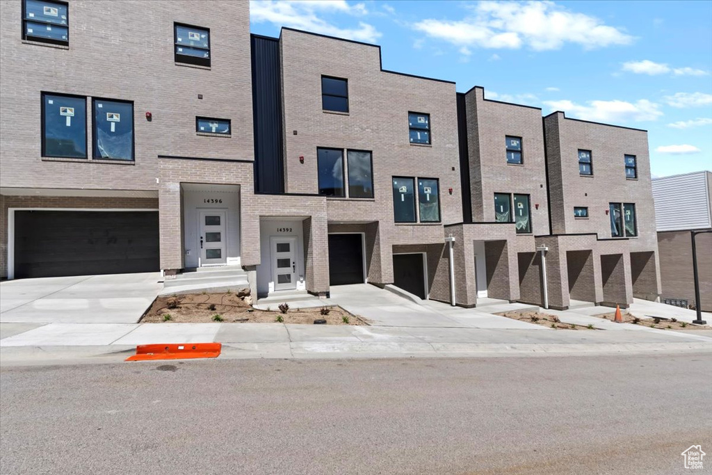 View of front of home featuring an attached garage, driveway, and brick siding