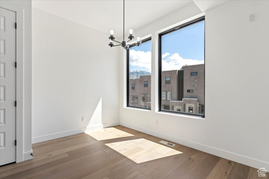 Unfurnished dining area with baseboards, wood finished floors, and a chandelier