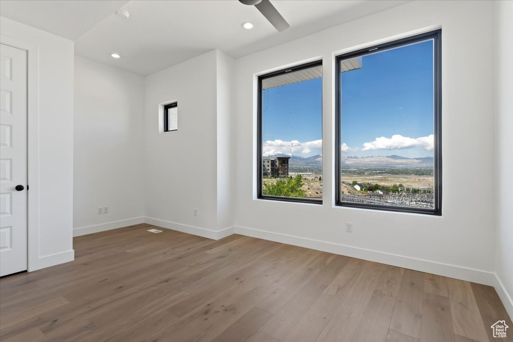 Empty room with plenty of natural light, baseboards, wood finished floors, and recessed lighting
