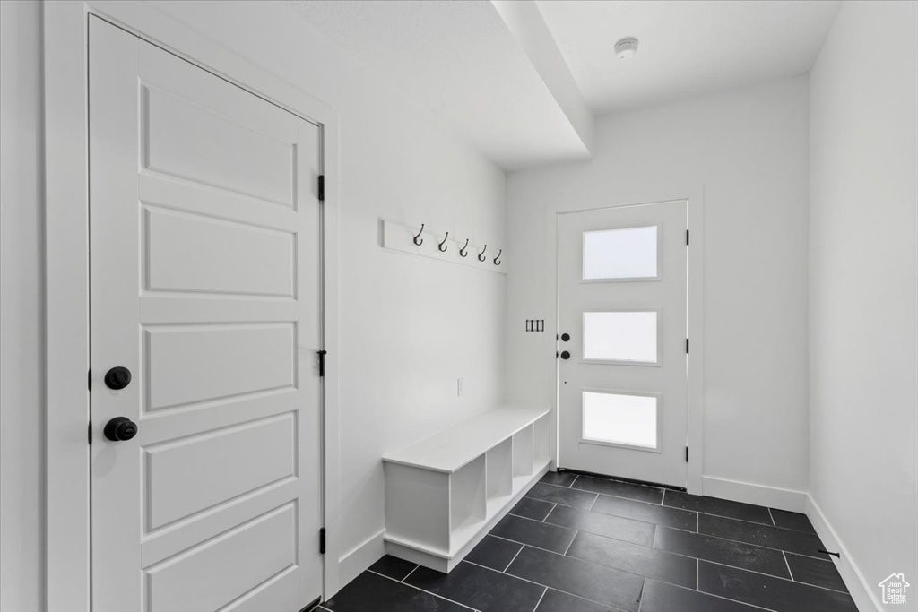 Mudroom featuring baseboards and dark tile patterned flooring
