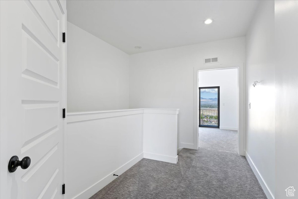 Hallway with an upstairs landing, carpet flooring, and baseboards