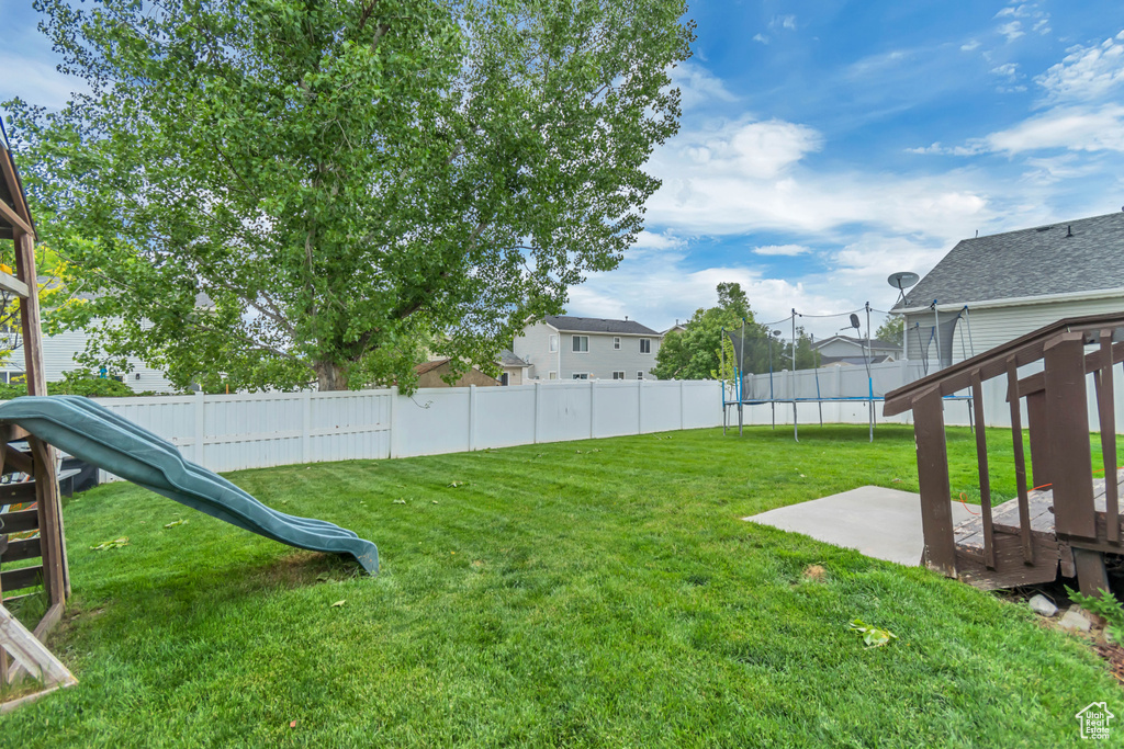 View of yard with a trampoline, a patio, and a playground