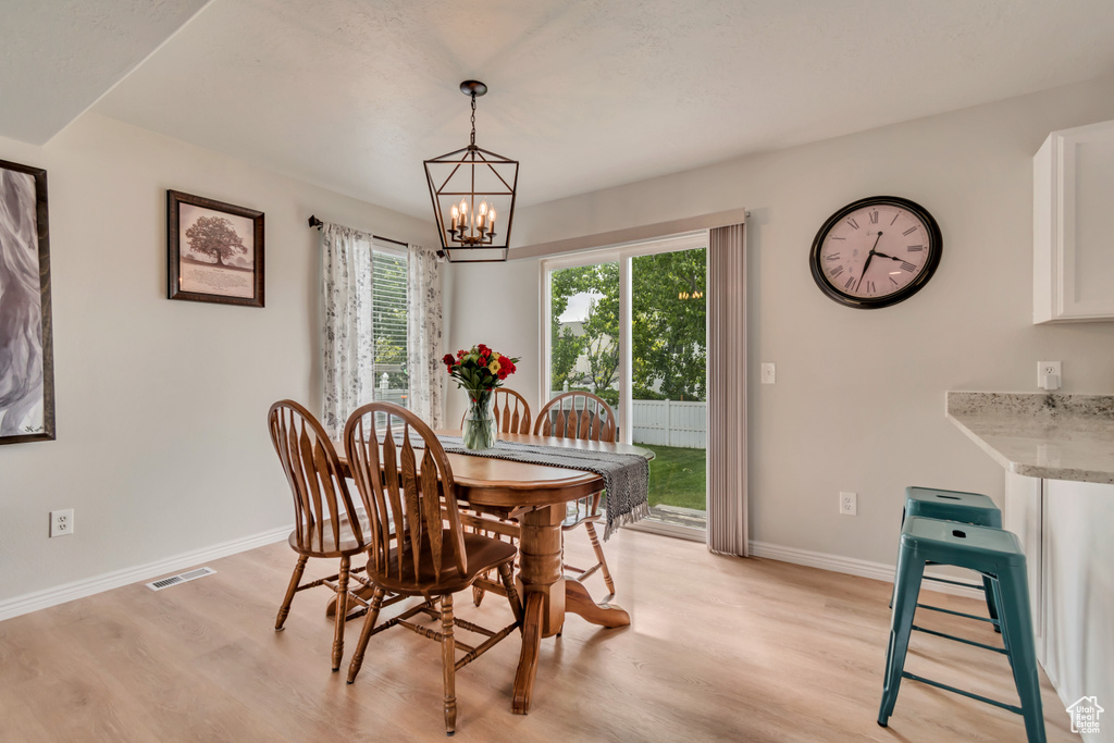 Dining room featuring light wood-style flooring, a chandelier, and baseboards