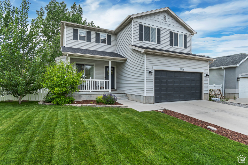 View of front of home with a porch, a garage, a front lawn, and driveway