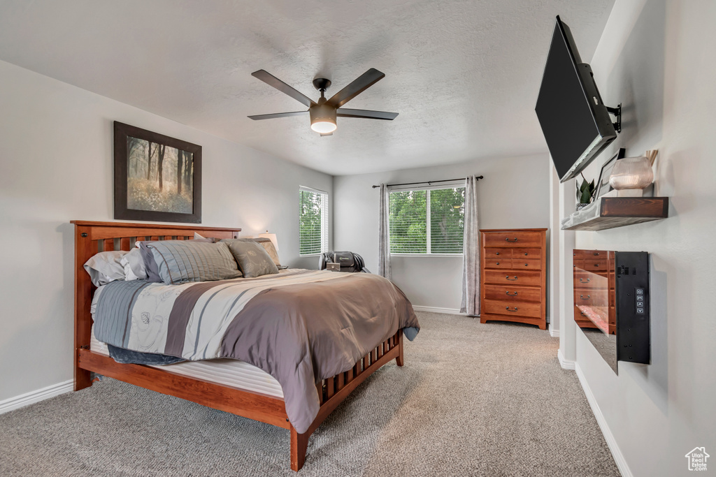 Bedroom featuring carpet floors, baseboards, ceiling fan, and a textured ceiling