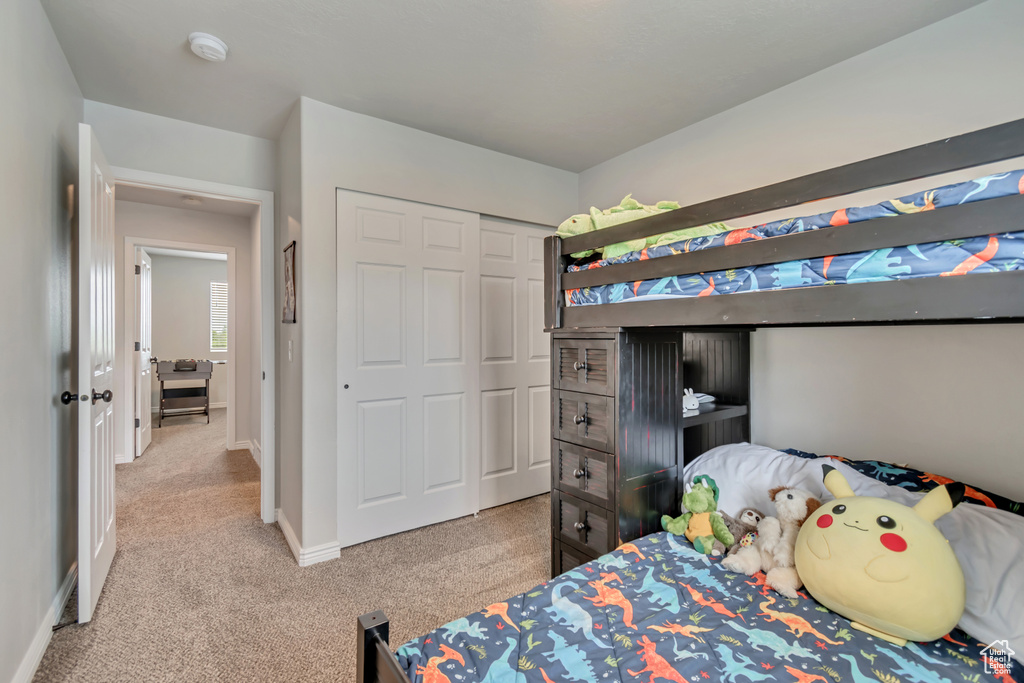 Bedroom featuring light carpet, a closet, and baseboards