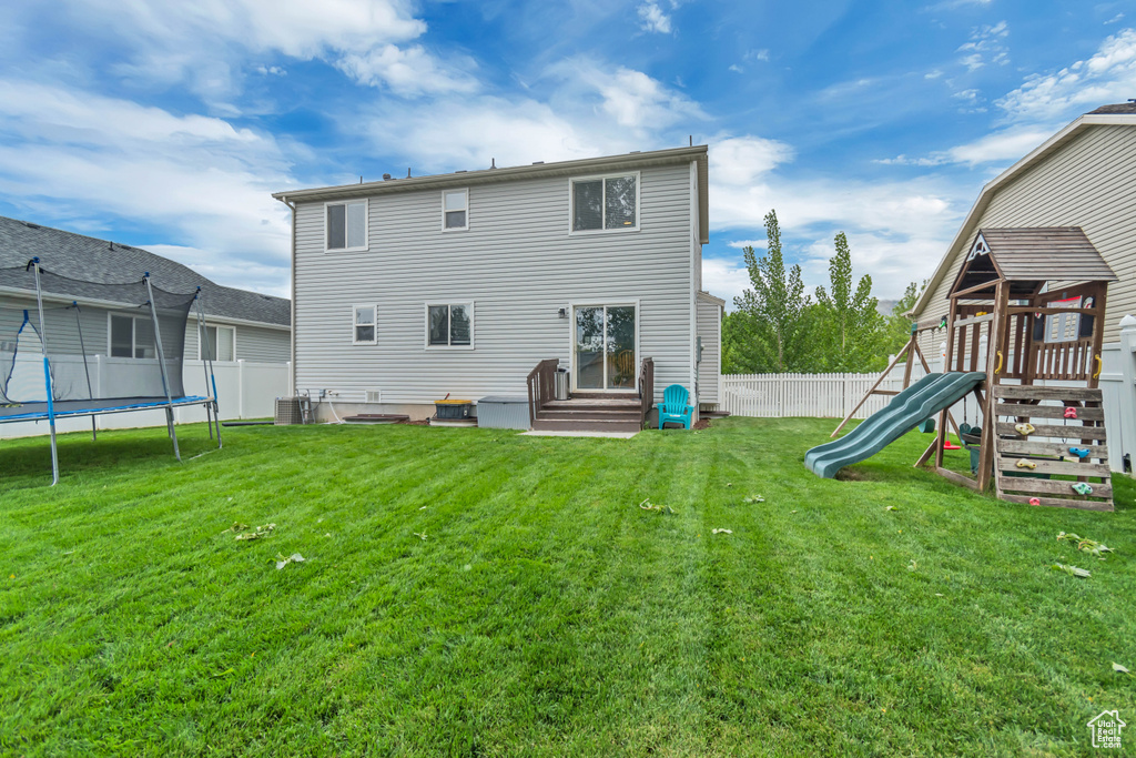 Back of property featuring a trampoline, a playground, central AC, and entry steps