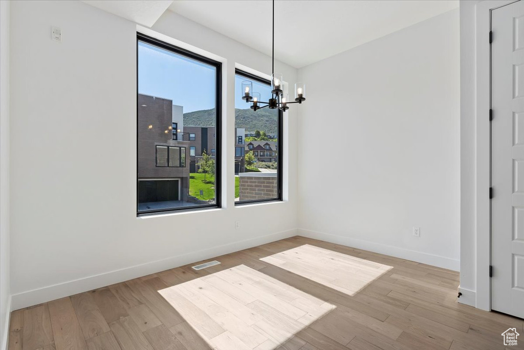 Unfurnished dining area with a chandelier, baseboards, and wood finished floors