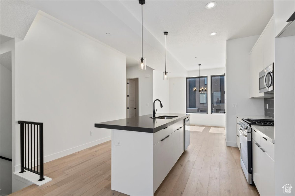 Kitchen featuring appliances with stainless steel finishes, a sink, modern cabinets, white cabinets, and recessed lighting
