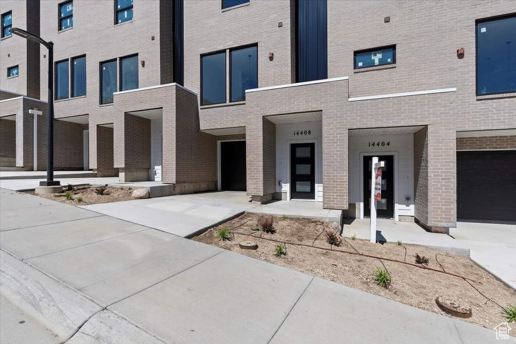 View of front facade with brick siding, driveway, and a garage