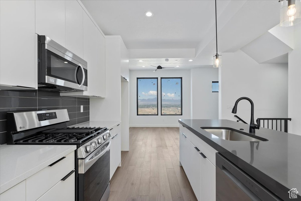 Kitchen featuring stainless steel appliances, a sink, modern cabinets, white cabinetry, and recessed lighting