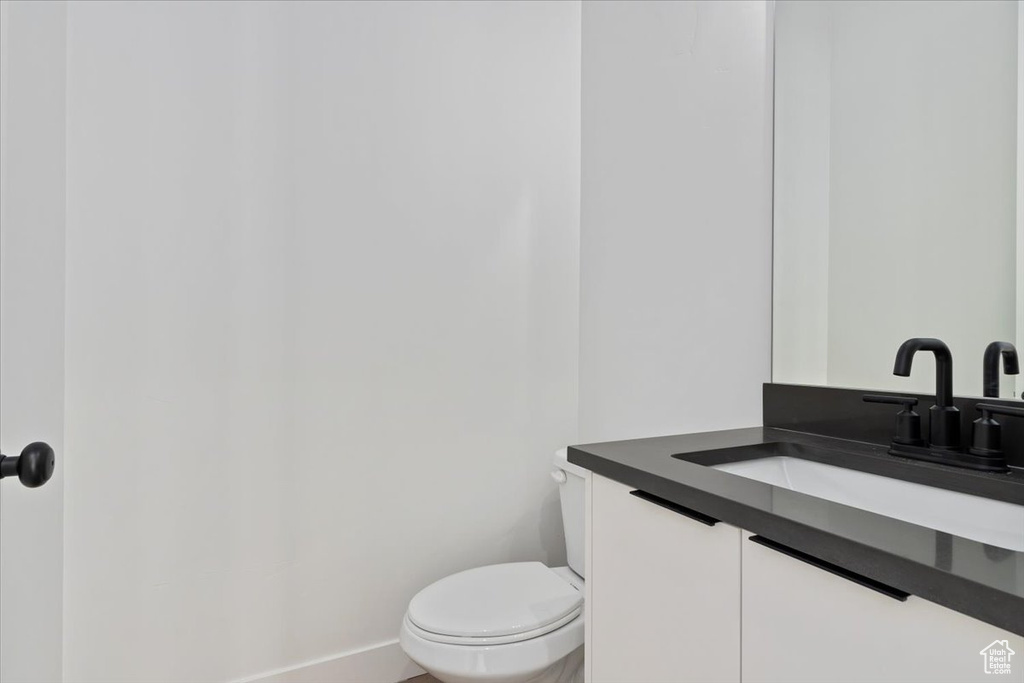 Bathroom with toilet, vanity, and baseboards