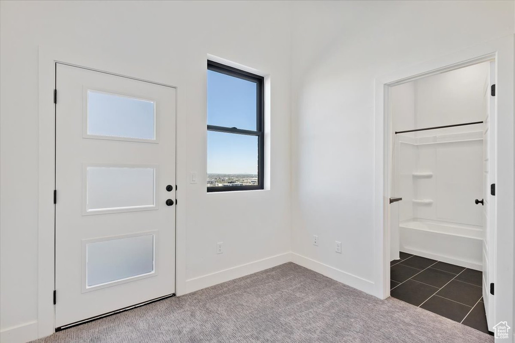 Doorway to outside featuring baseboards, carpet flooring, and tile patterned flooring