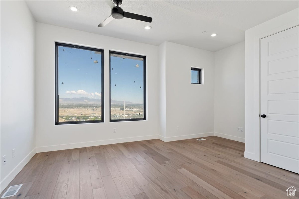 Unfurnished room featuring light wood-style flooring, a ceiling fan, baseboards, and recessed lighting