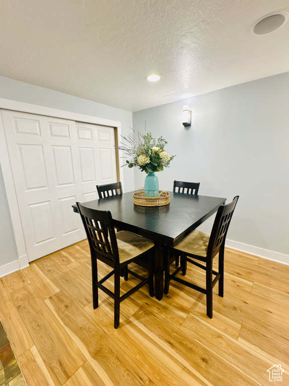 Dining area with light wood-type flooring, baseboards, a textured ceiling, and recessed lighting