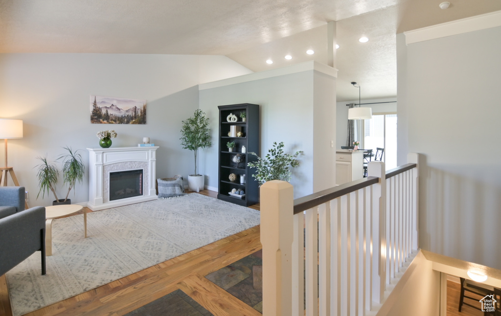 Living room with lofted ceiling, wood finished floors, a fireplace, and recessed lighting