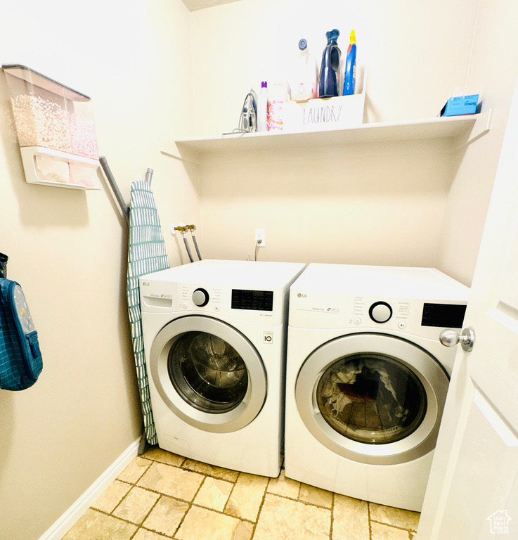 Laundry room featuring washer and dryer, stone tile floors, and baseboards