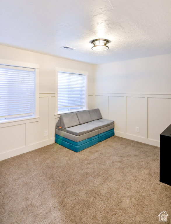 Bedroom with a decorative wall, carpet floors, a wainscoted wall, and a textured ceiling