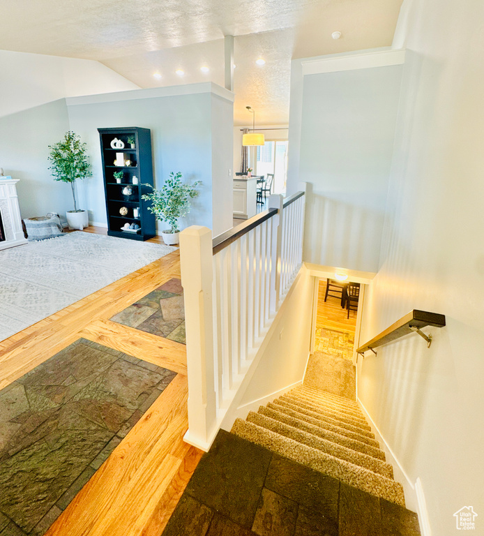 Staircase with wood finished floors, baseboards, and lofted ceiling