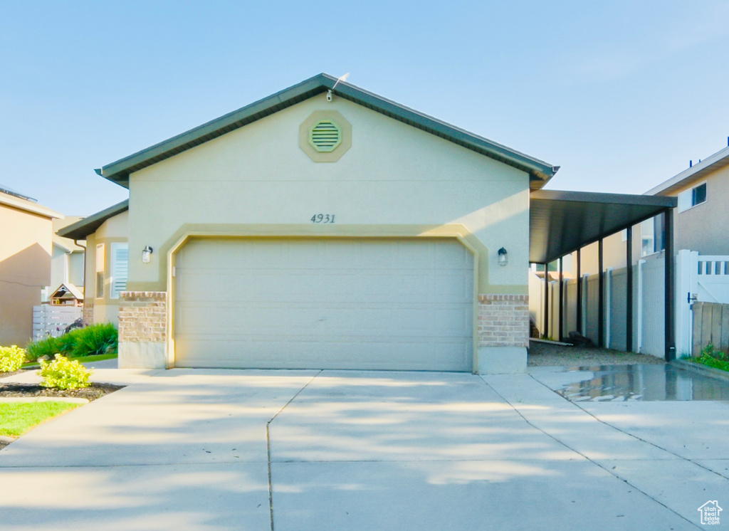 View of front of property featuring a garage, driveway, fence, and brick siding