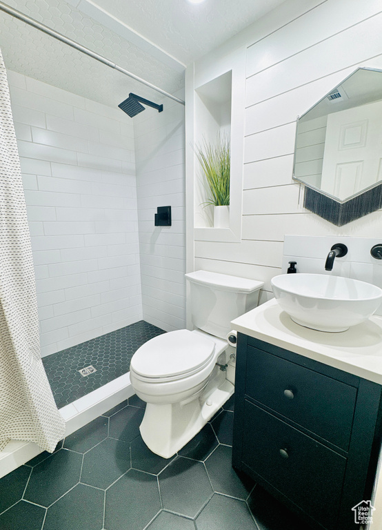 Bathroom featuring a stall shower, tile patterned flooring, toilet, and vanity