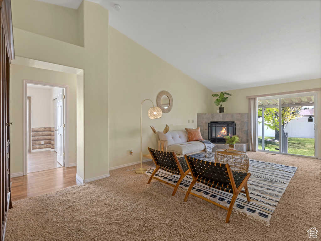 Living room with light carpet, a fireplace, high vaulted ceiling, and baseboards