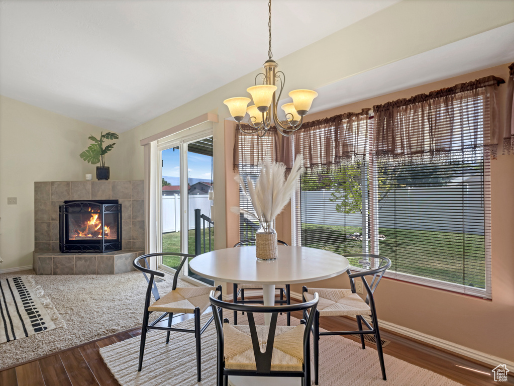 Dining area with wood finished floors, baseboards, a tiled fireplace, and a chandelier