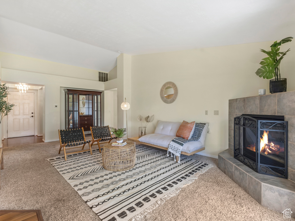 Living area featuring carpet, lofted ceiling, a tiled fireplace, and baseboards