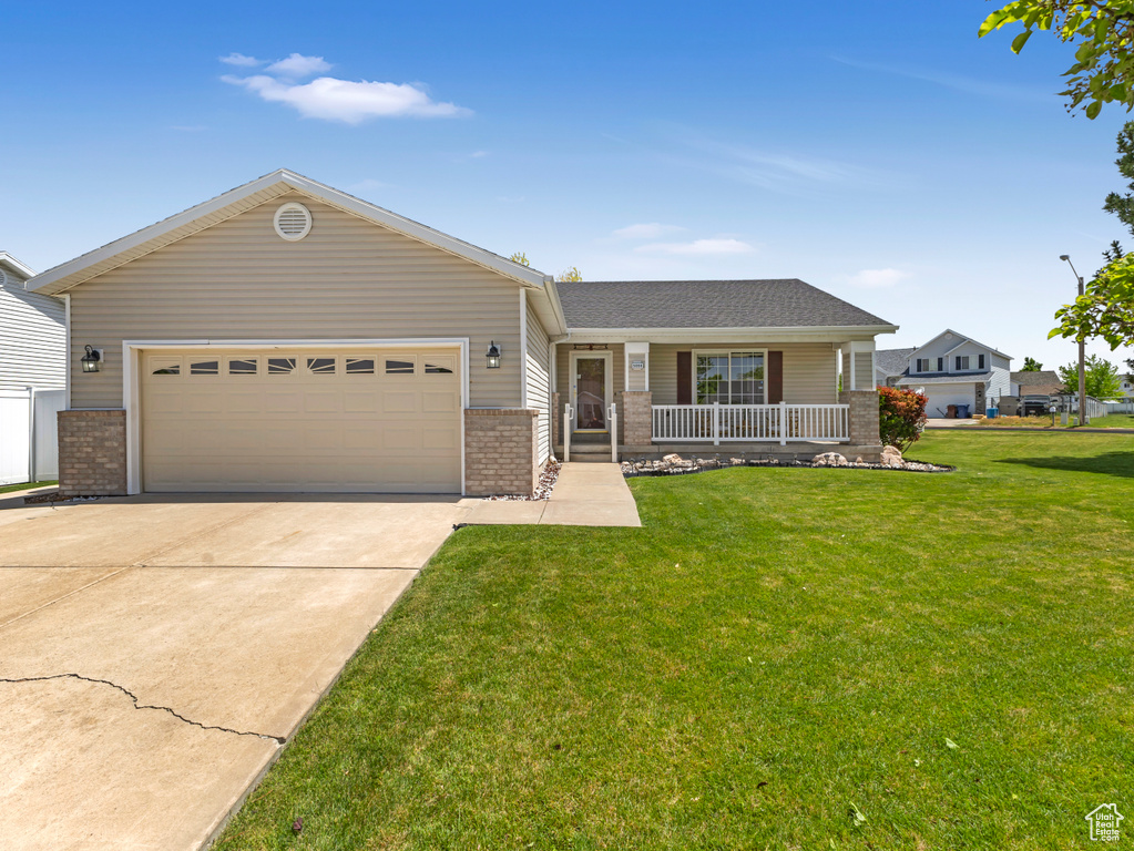 Single story home featuring brick siding, covered porch, driveway, and an attached garage