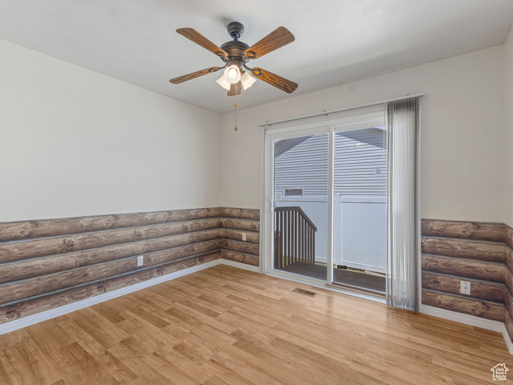 Spare room featuring light wood-type flooring, a ceiling fan, log walls, and baseboards