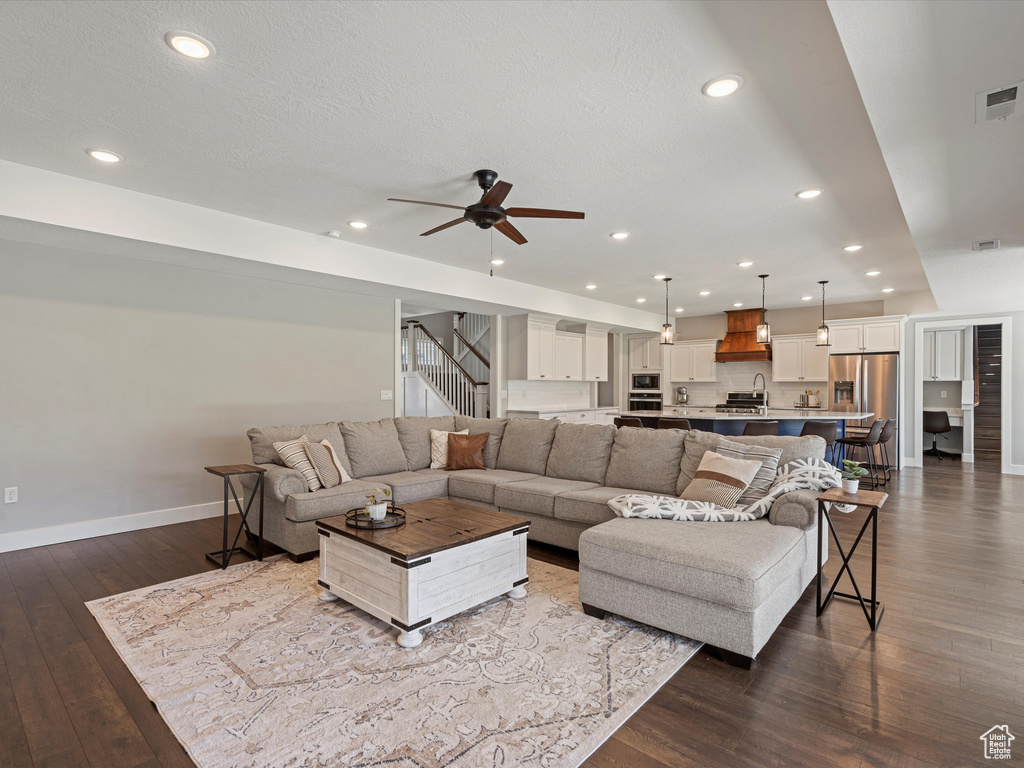Living room with dark wood-style flooring, a ceiling fan, baseboards, recessed lighting, and stairway