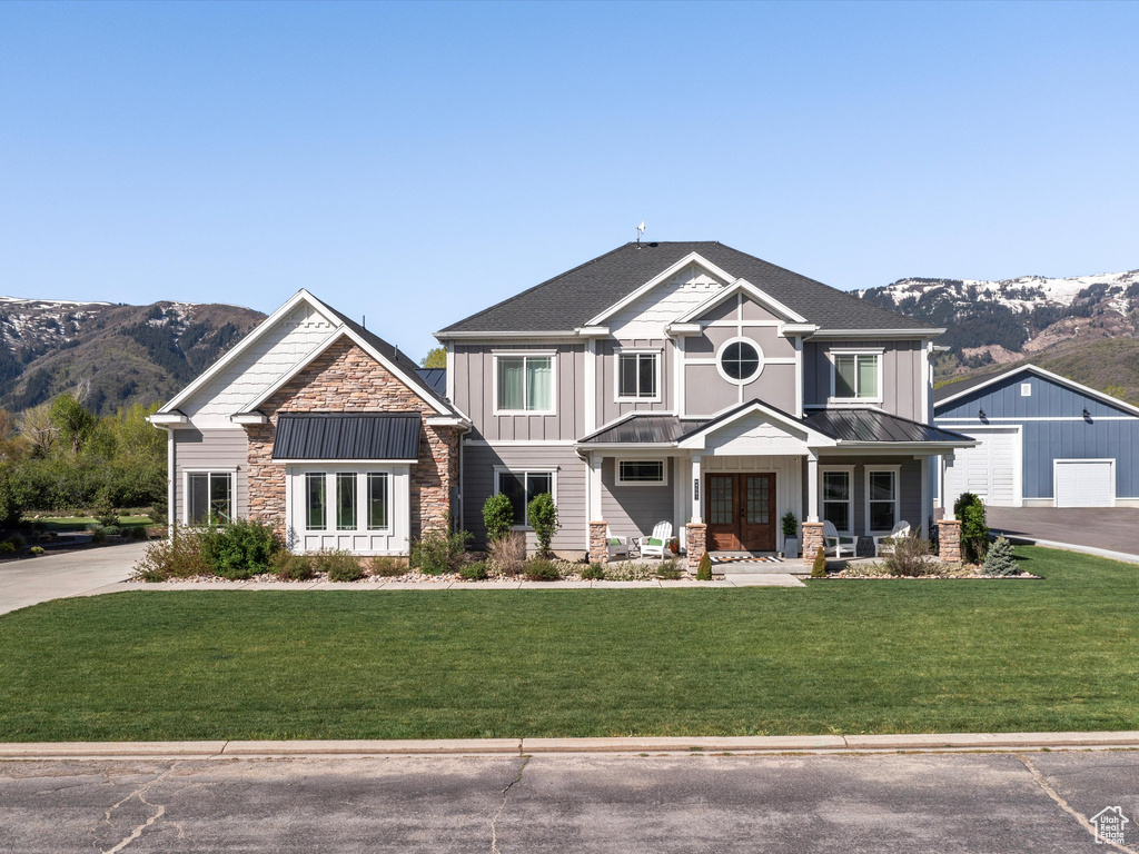 Craftsman-style house featuring a standing seam roof, a mountain view, board and batten siding, and a front lawn