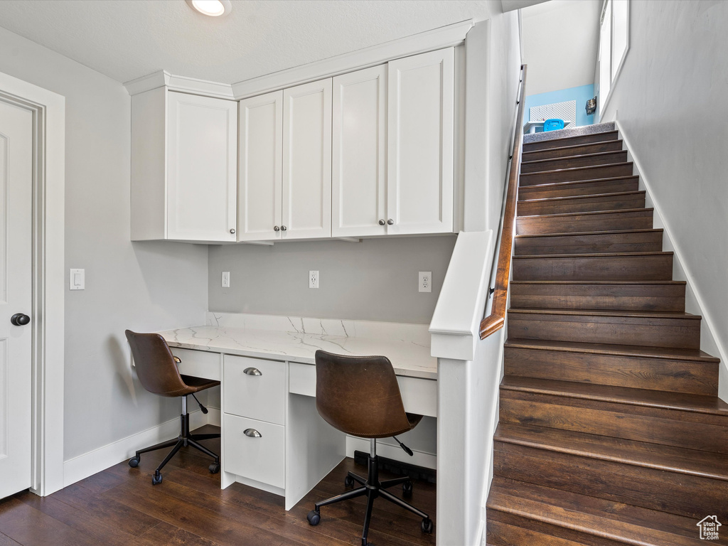 Home office with built in study area, baseboards, and dark wood finished floors