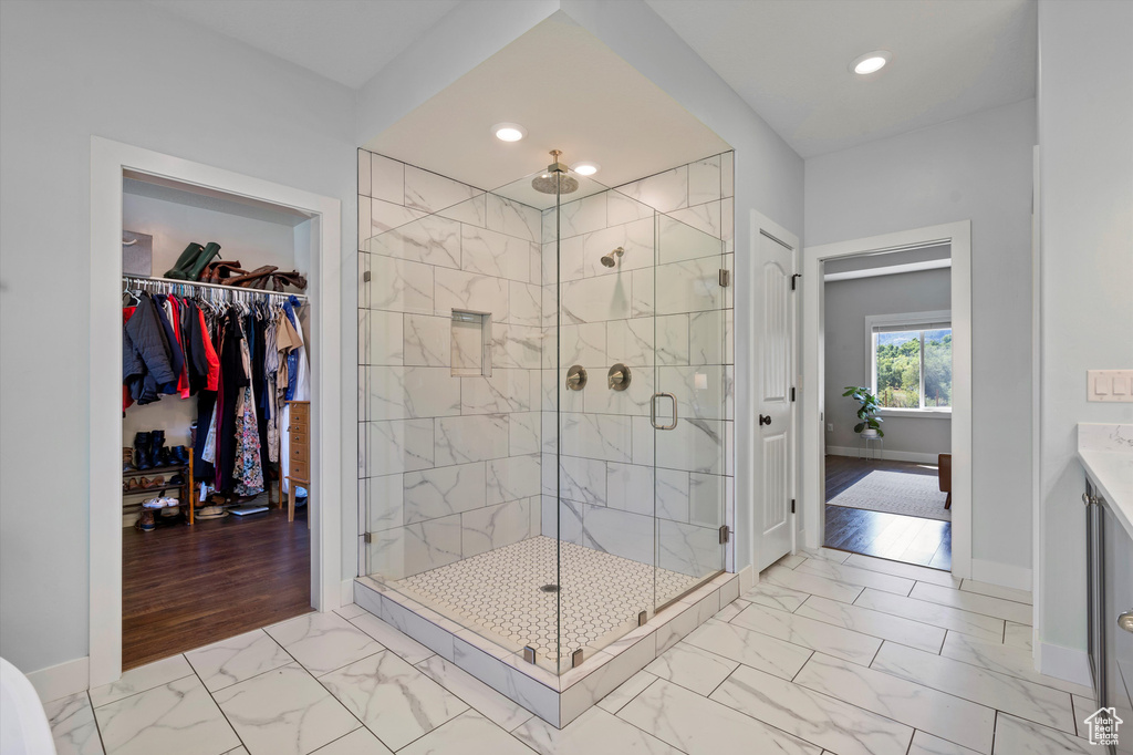 Bathroom featuring marble finish floors, a shower stall, baseboards, a spacious closet, and recessed lighting