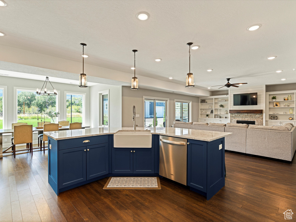 Kitchen featuring stainless steel dishwasher, a sink, blue cabinetry, ceiling fan, and plenty of natural light