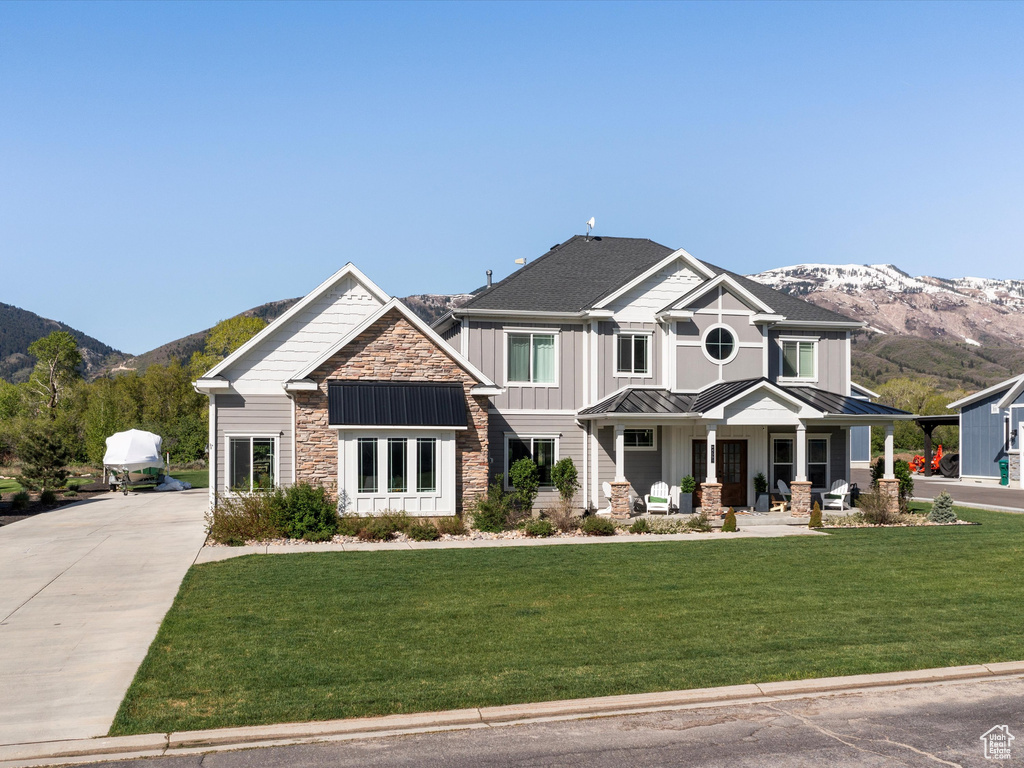 Craftsman house featuring a standing seam roof, a mountain view, a porch, and stone siding