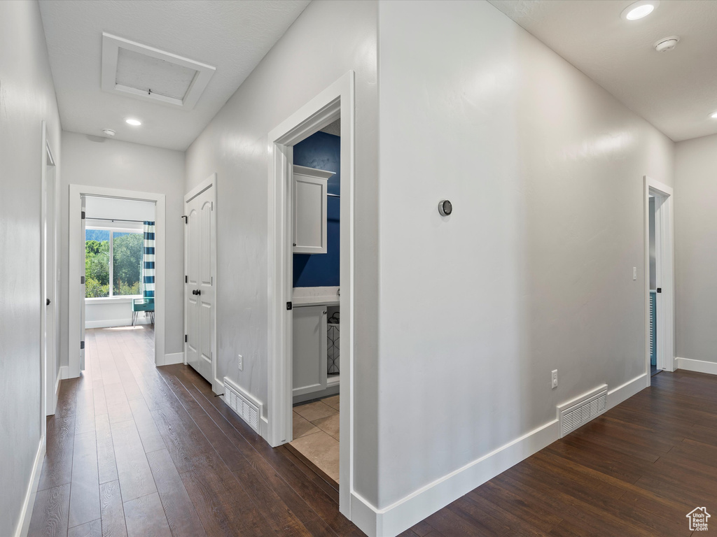 Hallway with dark wood-style floors, attic access, baseboards, and recessed lighting
