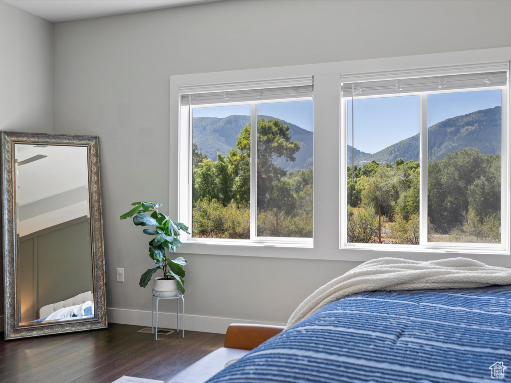 Bedroom with a mountain view, dark wood-style flooring, and baseboards