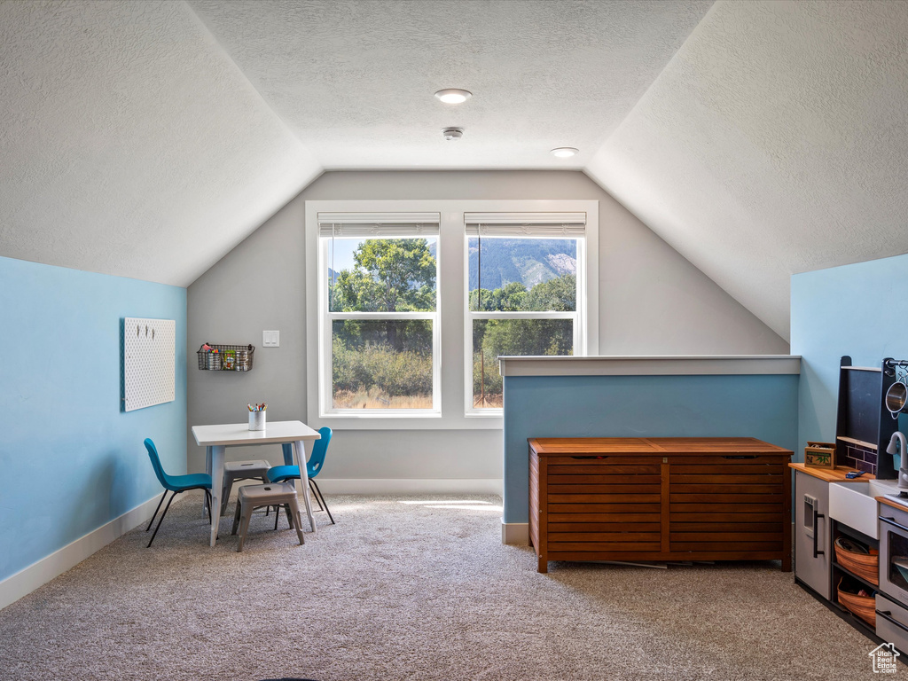 Rec room with vaulted ceiling, carpet flooring, a textured ceiling, and baseboards