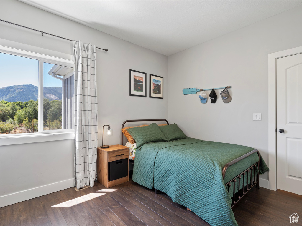 Bedroom featuring wood finished floors, a mountain view, and baseboards