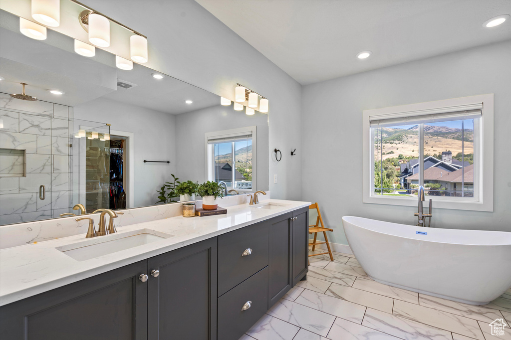 Full bathroom with marble look tile flooring, plenty of natural light, a shower stall, double vanity, and recessed lighting