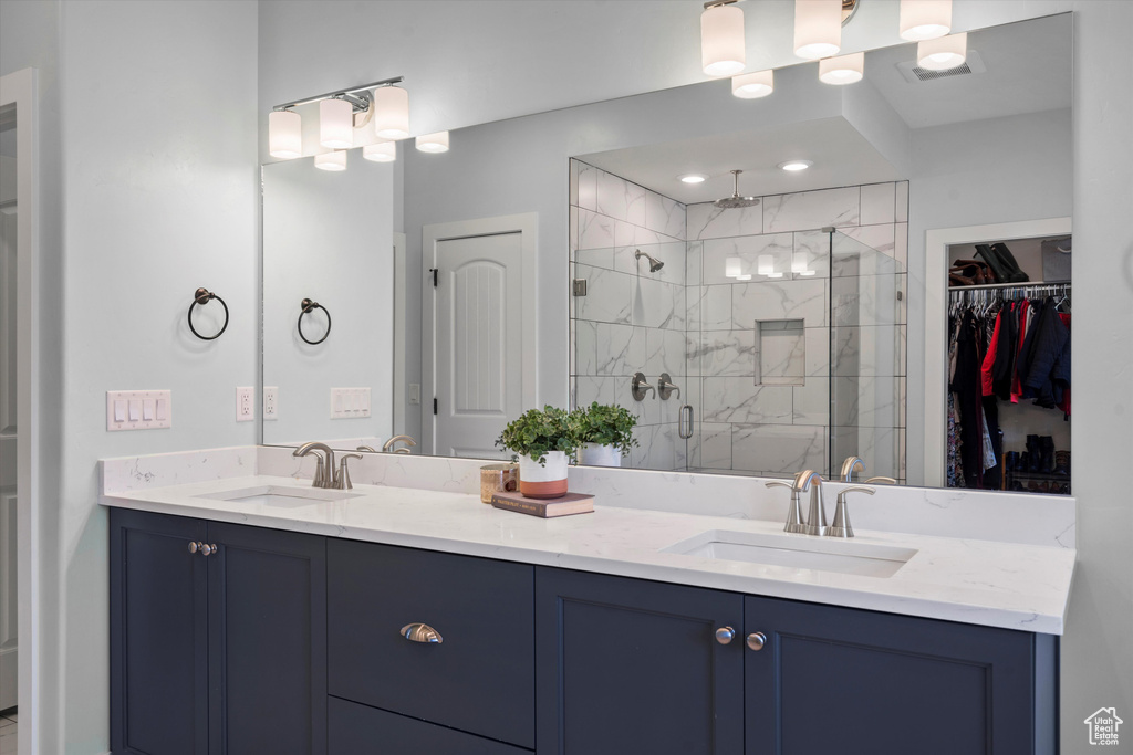 Full bathroom featuring a stall shower, double vanity, and a walk in closet