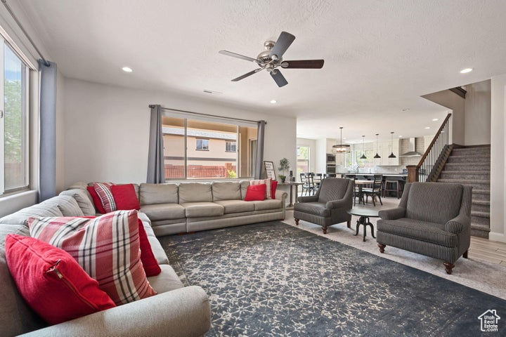Living area with plenty of natural light, a ceiling fan, stairway, and recessed lighting