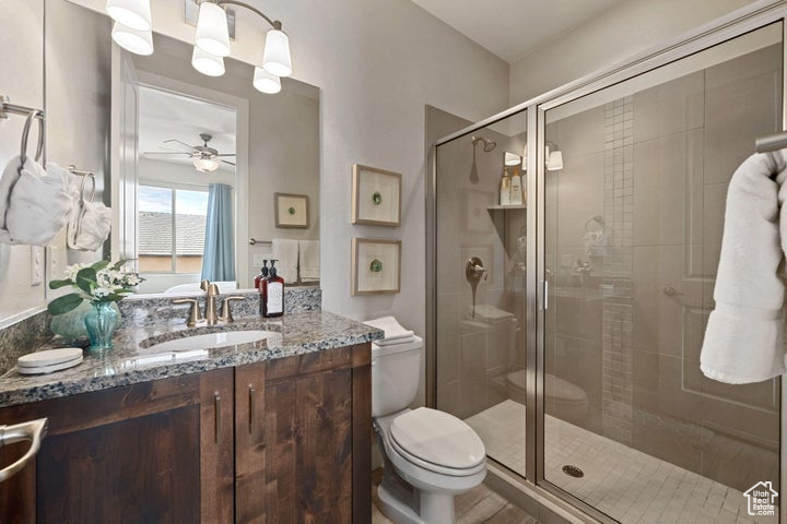 Bathroom with a stall shower, toilet, vanity, and ceiling fan