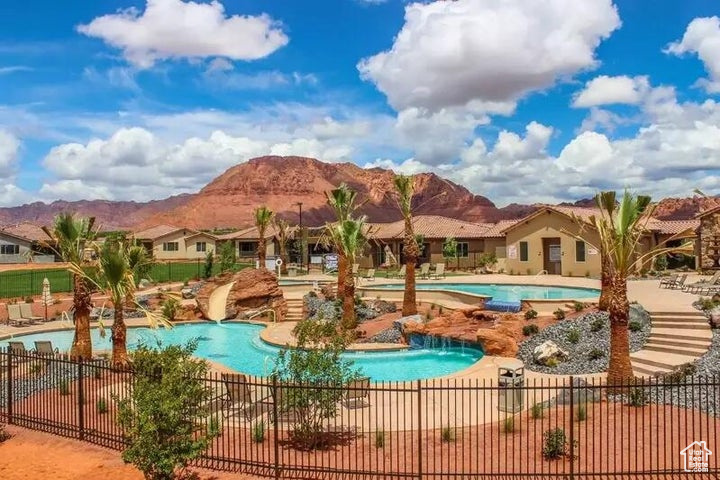 Community pool with fence, a mountain view, and a patio