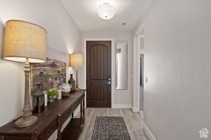 Doorway with light wood finished floors and baseboards