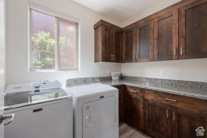 Laundry room featuring washer and clothes dryer, cabinet space, and light wood-type flooring